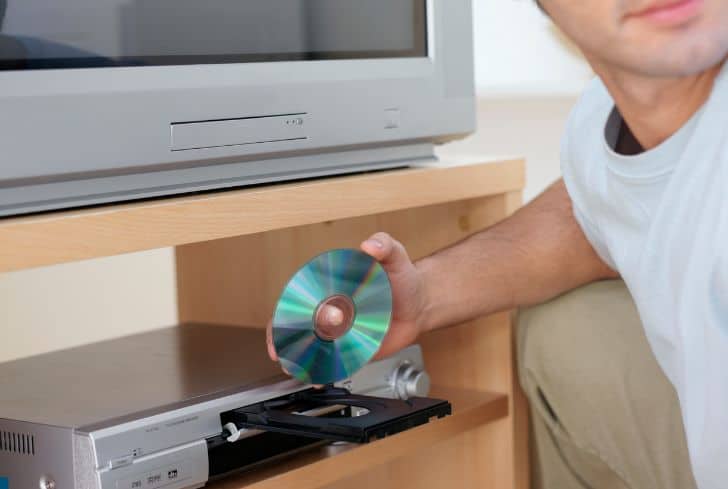 man-loading-cd-in-dvd-player